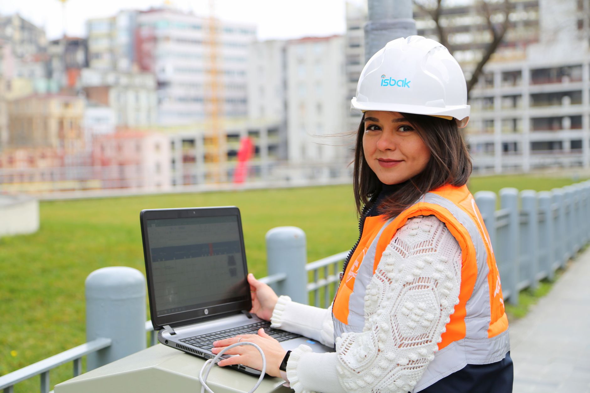 PROJE YÖNETİMİ EĞİTİMİ Sertifikası 1 A female engineer using a laptop at a construction site outdoors.