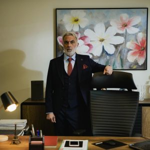 Distinguished mature businessman in a suit standing confidently in a modern office.