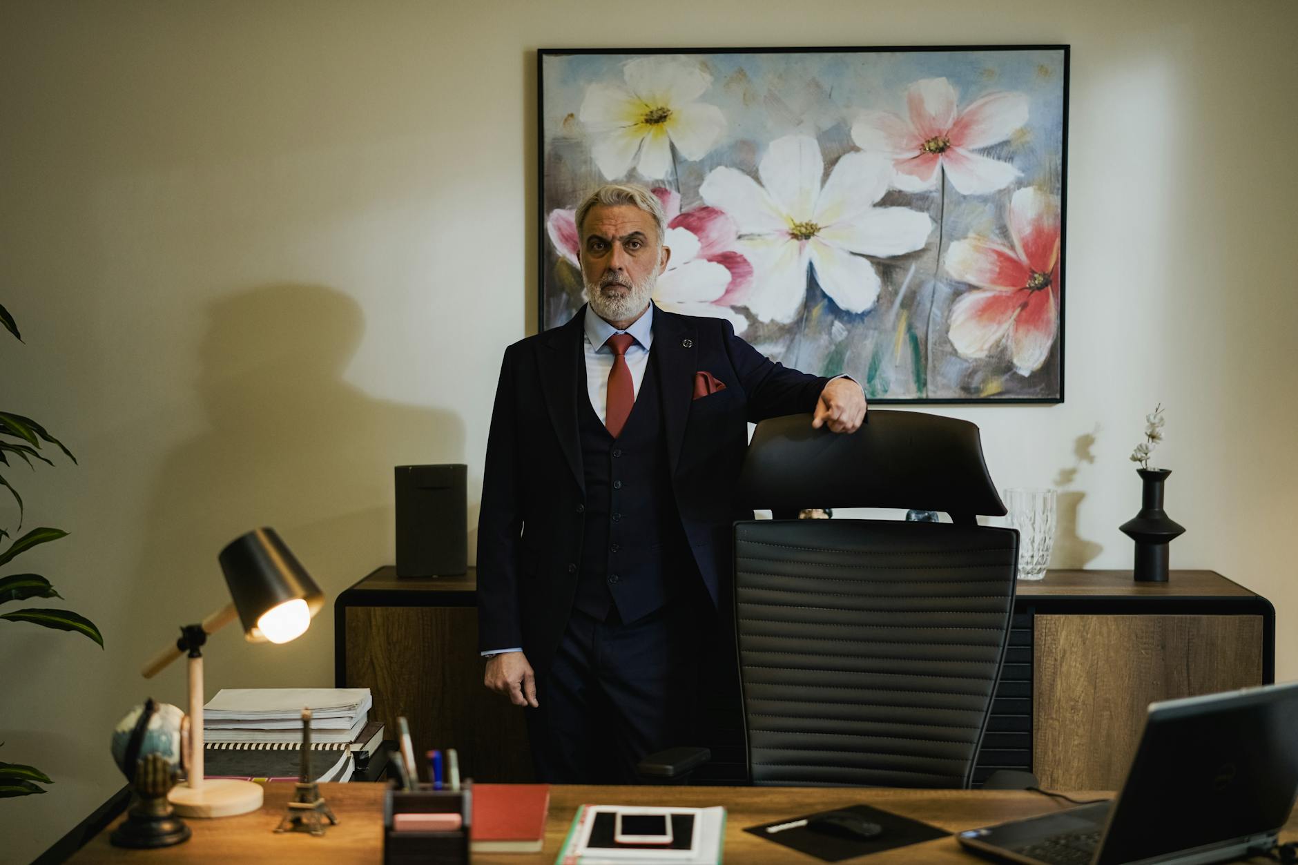 ÜST DÜZEY YÖNETİCİ EĞİTİMİ Sertifikası 1 Distinguished mature businessman in a suit standing confidently in a modern office.