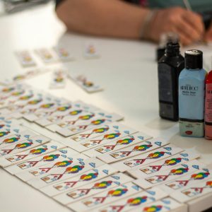 Creative workspace featuring paints, playing cards, and colored pencils, ideal for arts and crafts themes.