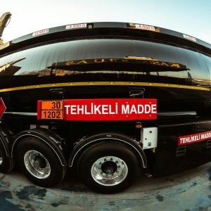 Wide-angle view of a black tank truck with hazard warning, highlighting its transportation purpose.