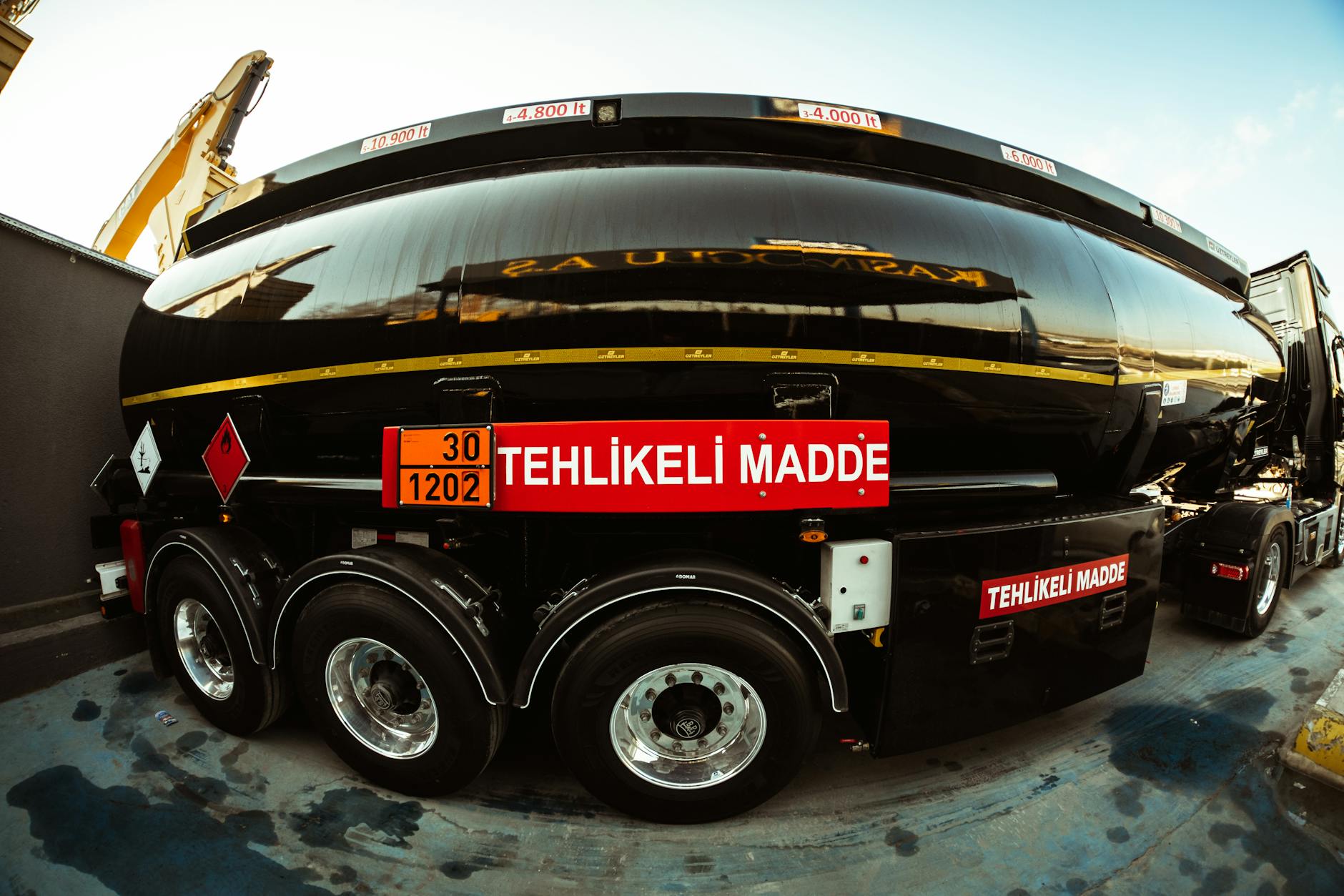 Yakıt Ölçü Elemanı eğitimi Sertifikası 1 Wide-angle view of a black tank truck with hazard warning, highlighting its transportation purpose.