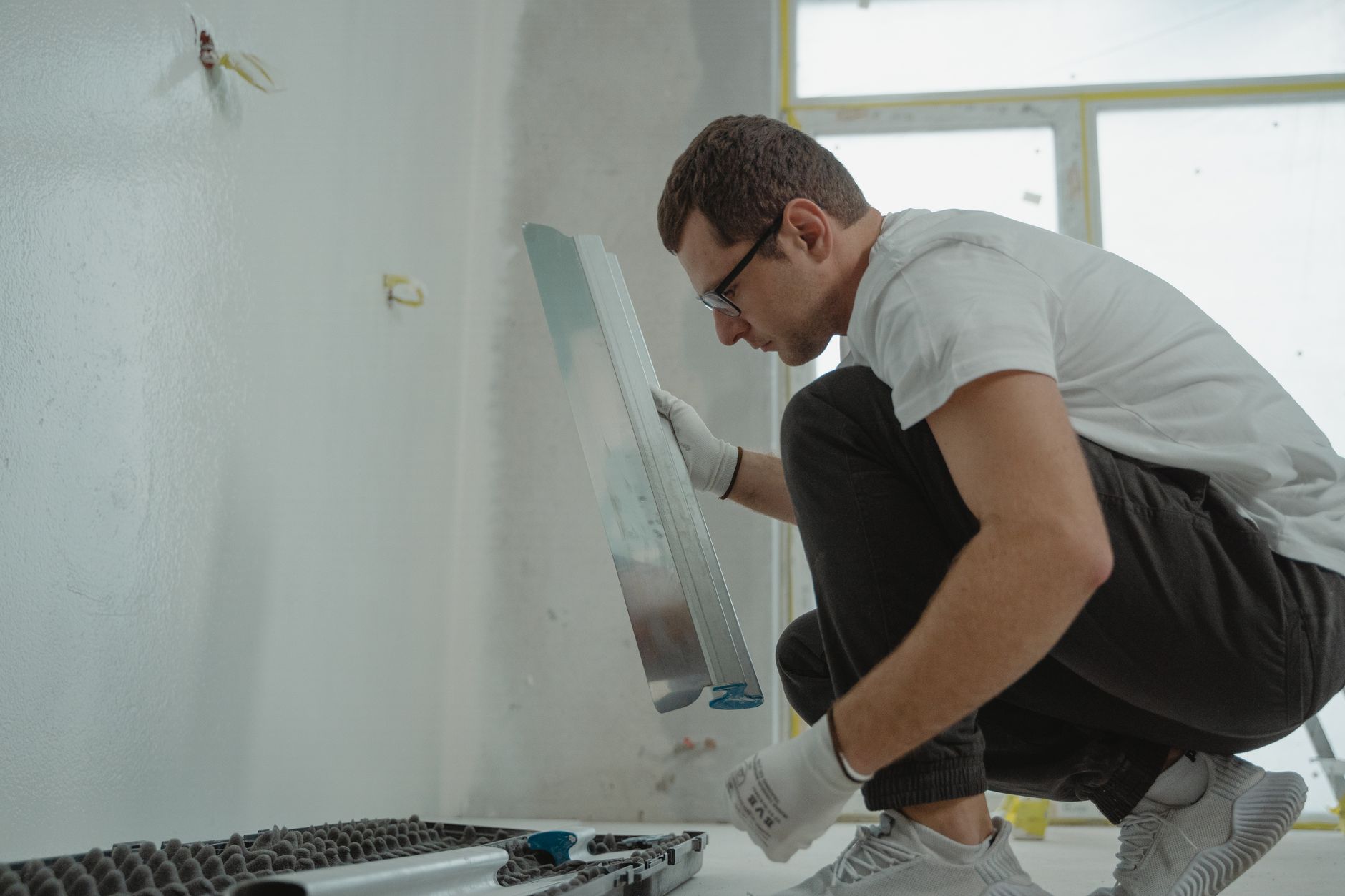 Alçıpan Ustalık Belgesi Nasıl Alınır? 9 Adult male using metal trowel in interior home renovation project. White walls.