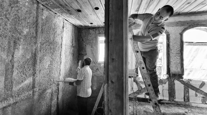 Mantolama İşi Yapmak İçin Hangi Belge Gerekir? 11 Two men renovating a room, one on a ladder applying plaster, showcasing teamwork and effort.
