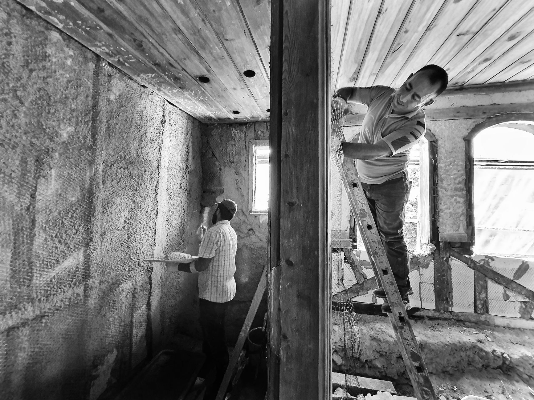 Mantolama İşi Yapmak İçin Hangi Belge Gerekir? 1 Two men renovating a room, one on a ladder applying plaster, showcasing teamwork and effort.