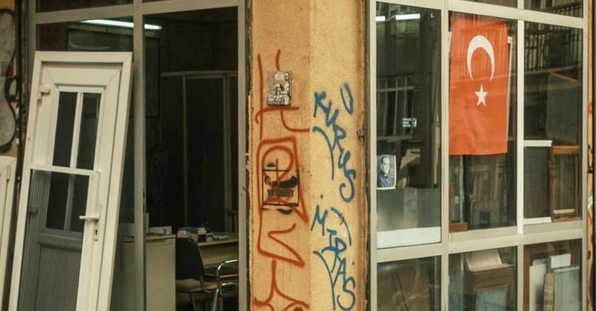 PVC Kapı Pencere Dükkanı Açmak İçin Hangi Belge Gerekir? 1 İstanbul'da bir dükkan girişinin ve Türk bayrağının yer aldığı, kentsel kültürü sergileyen bir sokak köşesi.