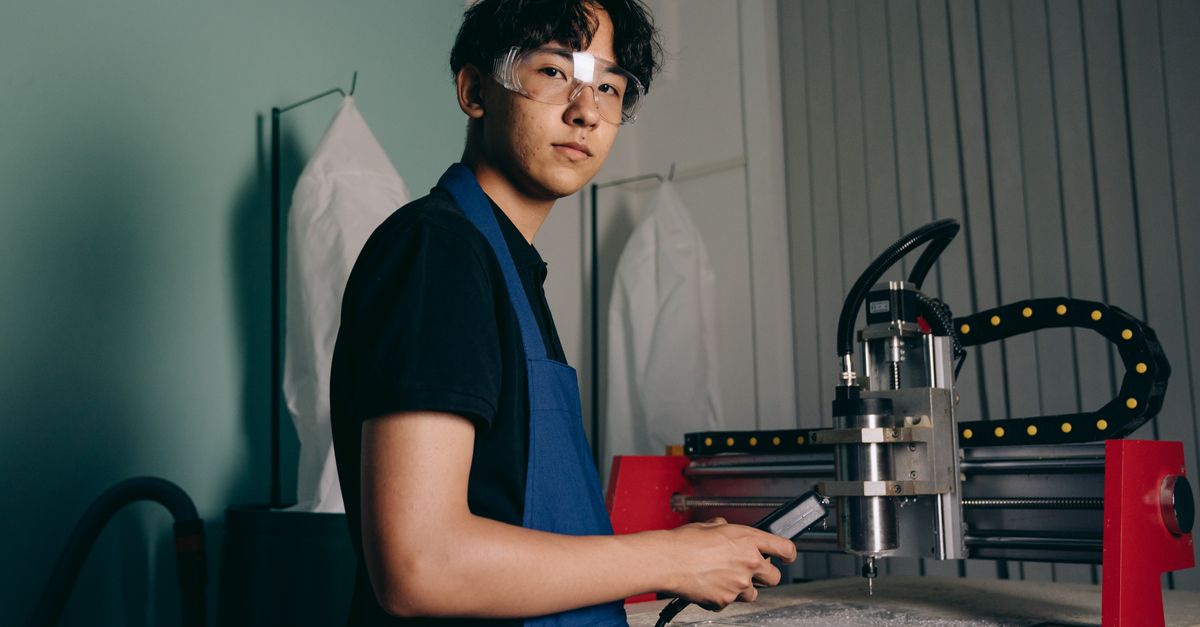 Etiketleme Kilitleme Sertifikası Nasıl Alınır? Kimler Katılabilir? 1 Güvenlik gözlüğü takmış Asyalı mühendis, bir CNC makinesi ile çalışıyor. Kapalı endüstriyel ortam.
