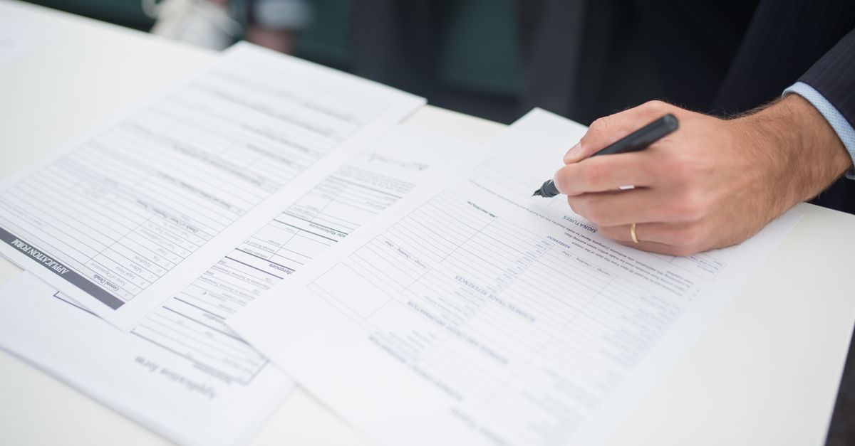 ISO 19011 İç Denetçi Nasıl Olunur? Eğitim ve Yetkinlik Rehberi 1 Ofis ortamında sigorta belgelerini imzalayan bir elin yakın görünümü.