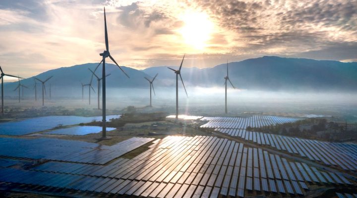 ISO 50001 Eğitimi Kimler İçin Uygundur? Enerji Yönetimi Sertifika Rehberi 1 Arka planda dağlar ve sis, rüzgar türbinleri ve güneş panellerinin gün doğumunda çekilmiş muhteşem hava fotoğrafı.