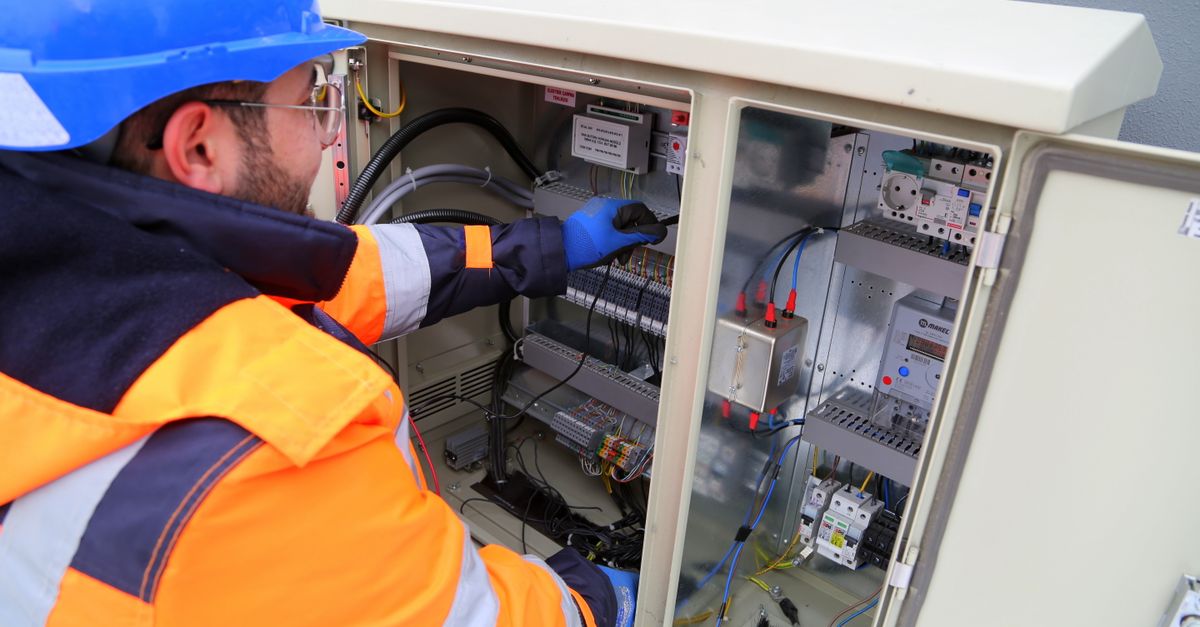 ISO 50001 Nedir? Enerji Yönetim Sistemi İşletmelere Ne Kazandırır? 1 Güvenlik ekipmanları giymiş mühendis, dış mekan elektrik panosunda çalışarak sistemin işlevselliğini sağlıyor.