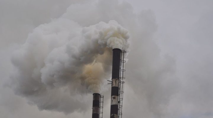 Karbon Ayak İzi Eğitimi Kimler İçin Uygundur? ISO 14064 Sertifika Rehberi 3 Kapalı gökyüzüne yoğun duman püskürten iki baca, endüstriyel kirliliği gözler önüne seriyor.