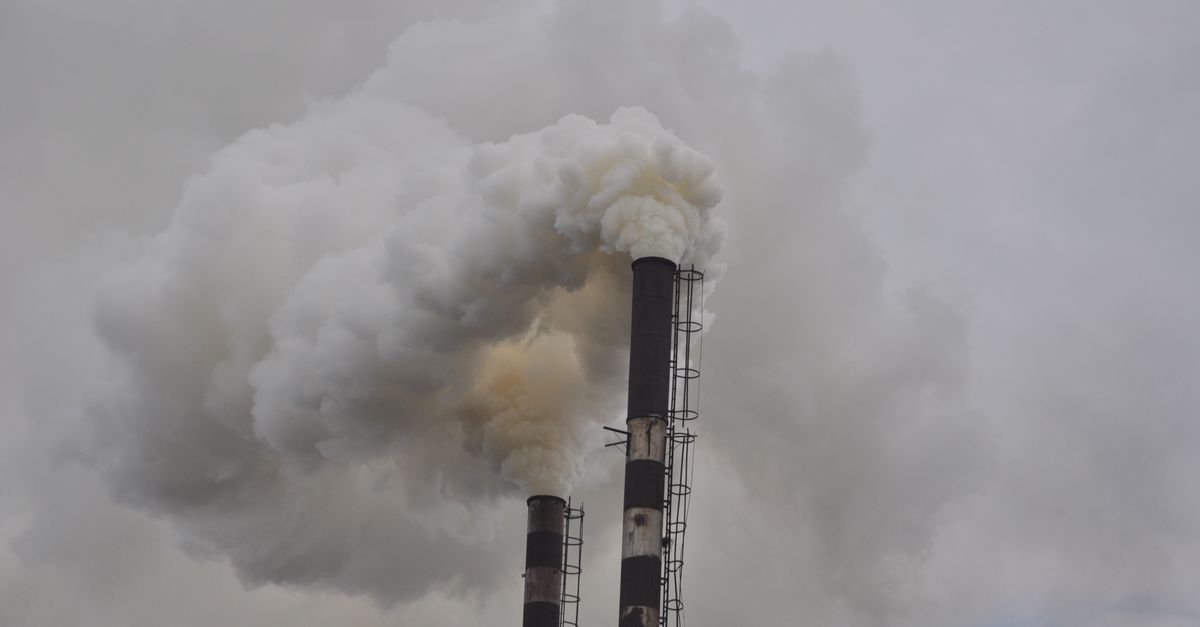 Karbon Ayak İzi Eğitimi Kimler İçin Uygundur? ISO 14064 Sertifika Rehberi 5 Kapalı gökyüzüne yoğun duman püskürten iki baca, endüstriyel kirliliği gözler önüne seriyor.