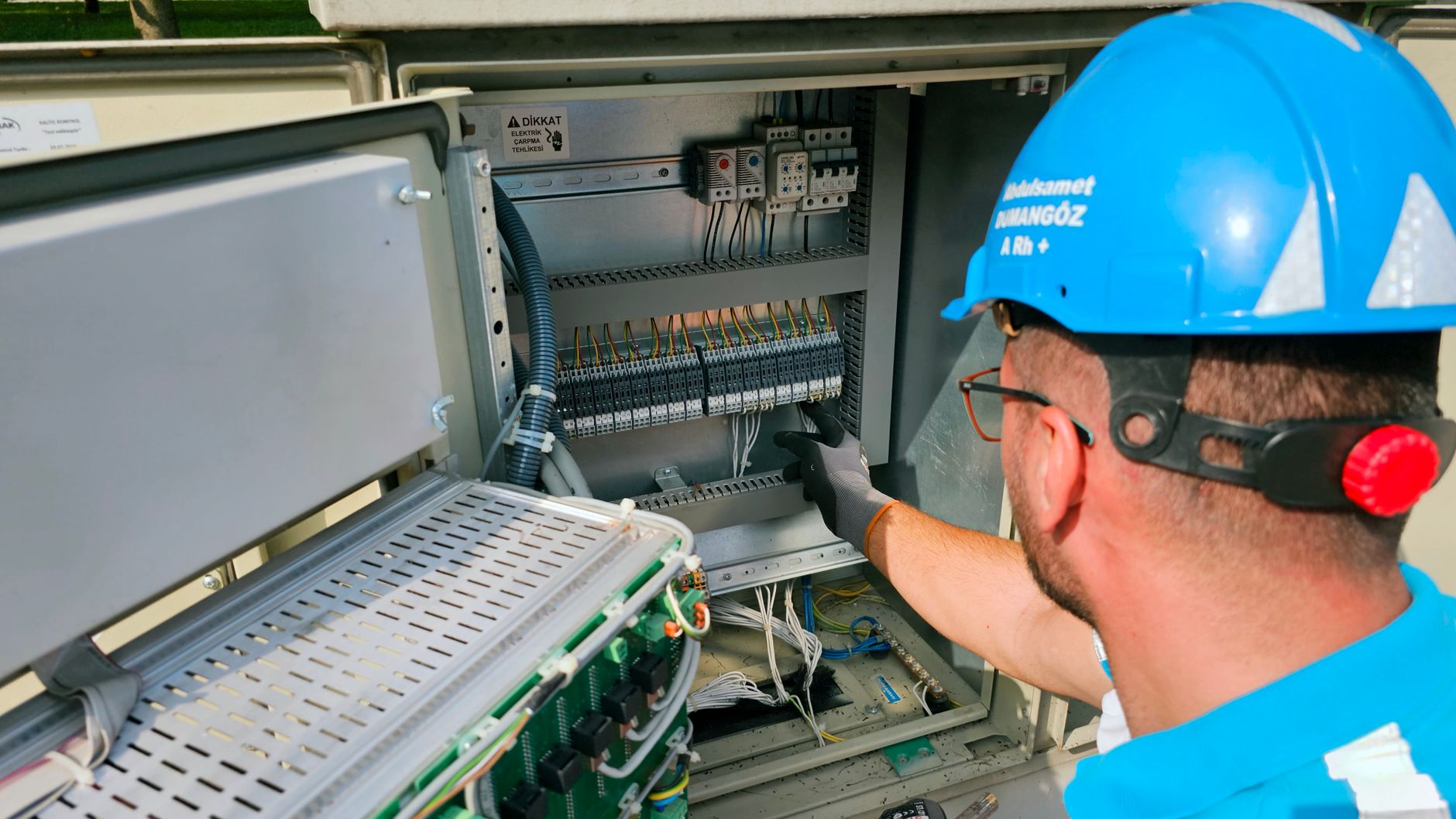 Montaj Personeli Ne İş Yapar? Görevleri ve Çalışma Alanları 1 An electrician works on an outdoor fusebox, ensuring safety and functionality.